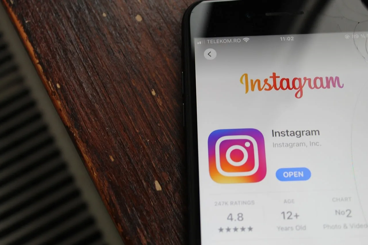 Top of a cell phone with the screen on, displaying the Instagram app, resting on a wooden board.