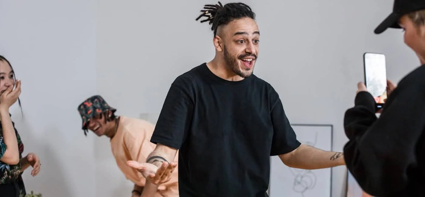 Four young people are recording a video for TikTok. One boy films with his cell phone, while another boy and two girls interact, laughing spontaneously. Buy TikTok views