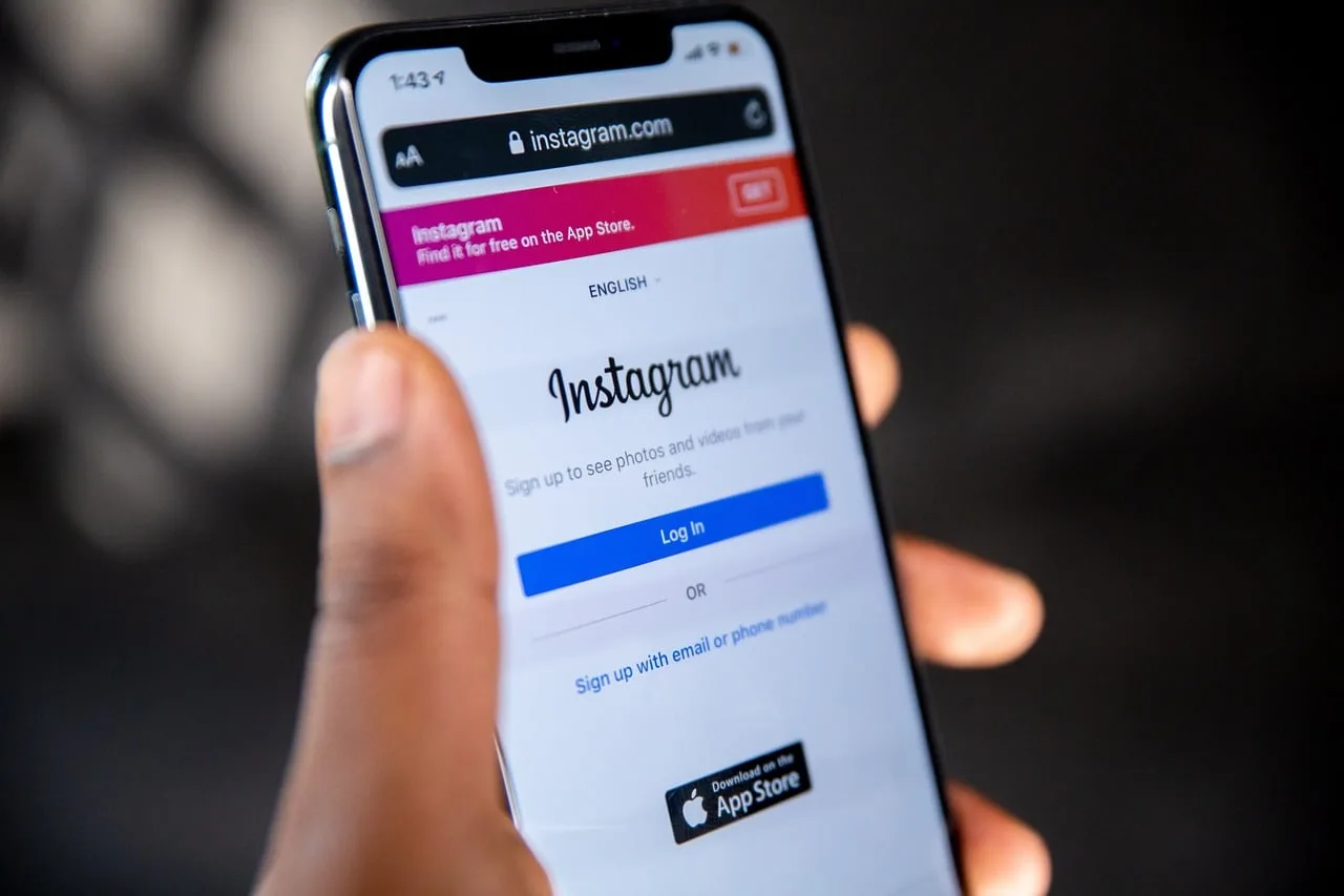 A close-up showing a person's hand holding a cell phone with the screen on, open to the Instagram app login screen.