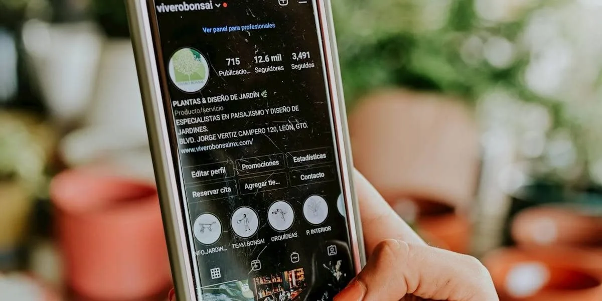 A cell phone with its screen on, displaying an Instagram profile and a business account username, is in the hands of a woman with neatly manicured nails.
