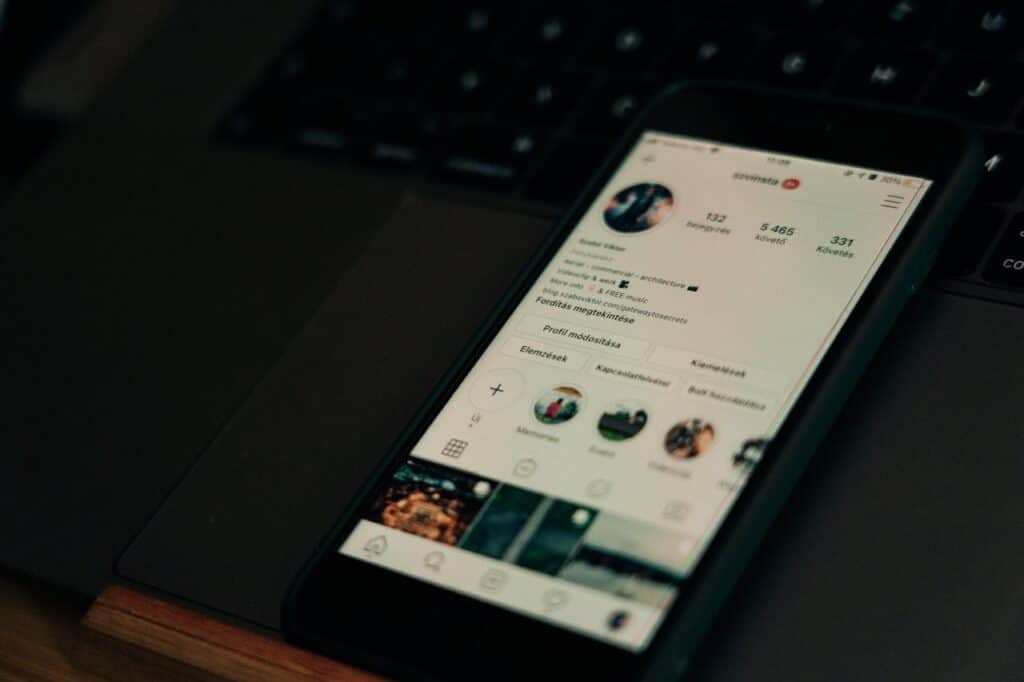 Um celular com a tela ligada, mostrando o perfil de um usuário do Instagram, sobre um teclado de notebook preto. Como saber quem visitou meu perfil no Instagram?
