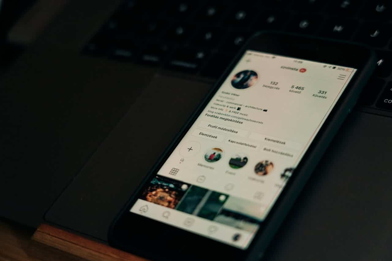 Um celular com a tela ligada, mostrando o perfil de um usuário do Instagram, sobre um teclado de notebook preto. Como saber quem visitou meu perfil no Instagram?