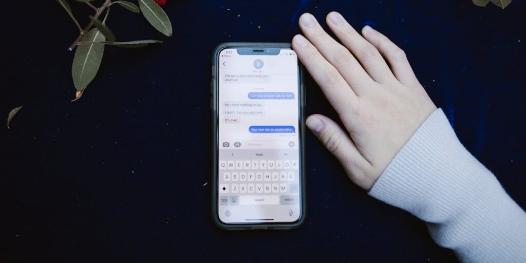 Celular com tela ligada no chat do Instagram, sobre toalha azul com tema natalino. Ao lado, vemos a mão de uma pessoa. Como recuperar conversas apagadas do Instagram.