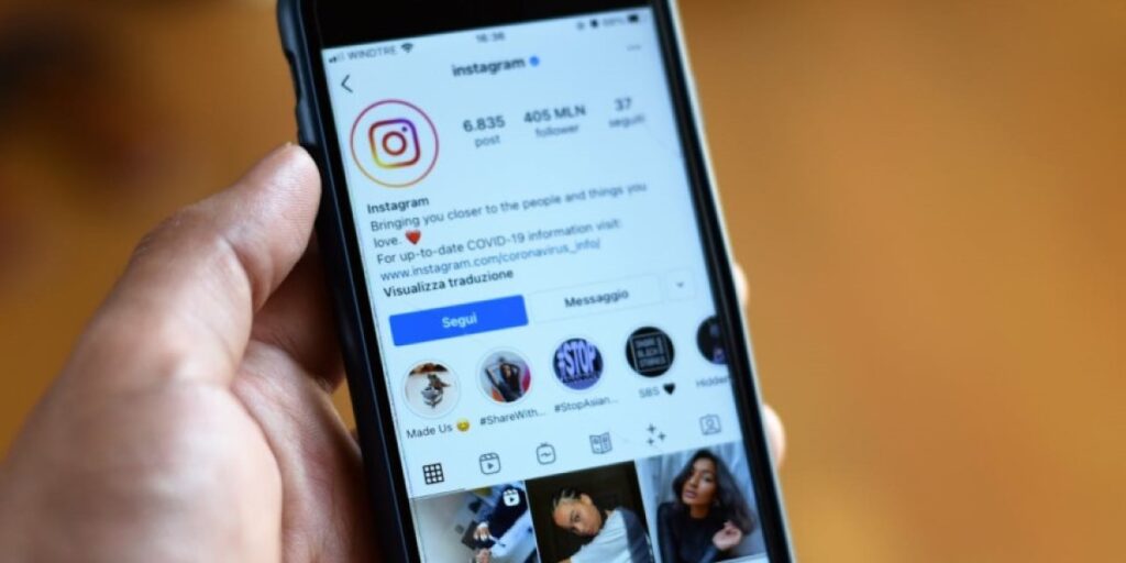Detalhe mostrando a mão de uma pessoa segurando o celular. A tela está ligada exibindo o perfil do Instagram de um usuário. O que é restringir no Instagram?