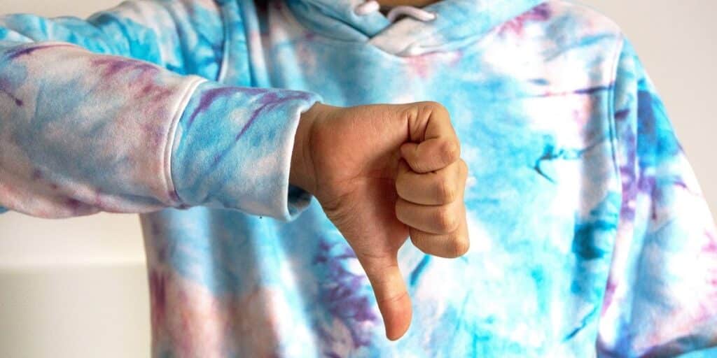 Homem com moletom colorido, com estampa que lembra manchas de tinta, faz sinal de negativo com a mão a frente do peito. Não vemos sua cabeça, apenas seu tórax. Como saber quem deixou de me seguir no Instagram.