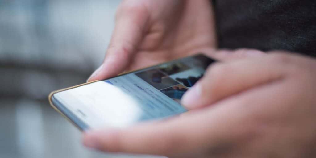 Detalhe mostrando celular nas mãos de usuário, aberto em rede social. Como marcar alguém no Instagram.