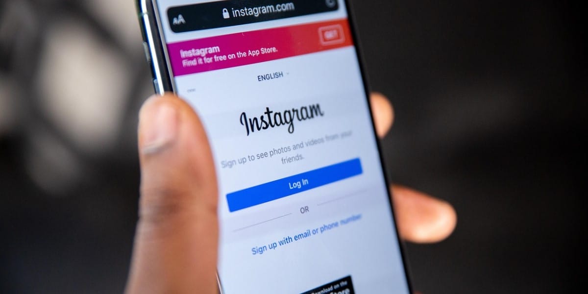 Detalhe mostrando a mão de uma pessoa, segurando o celular com tela ligada na página de login do Instagram. Como mudar a senha do Instagram.