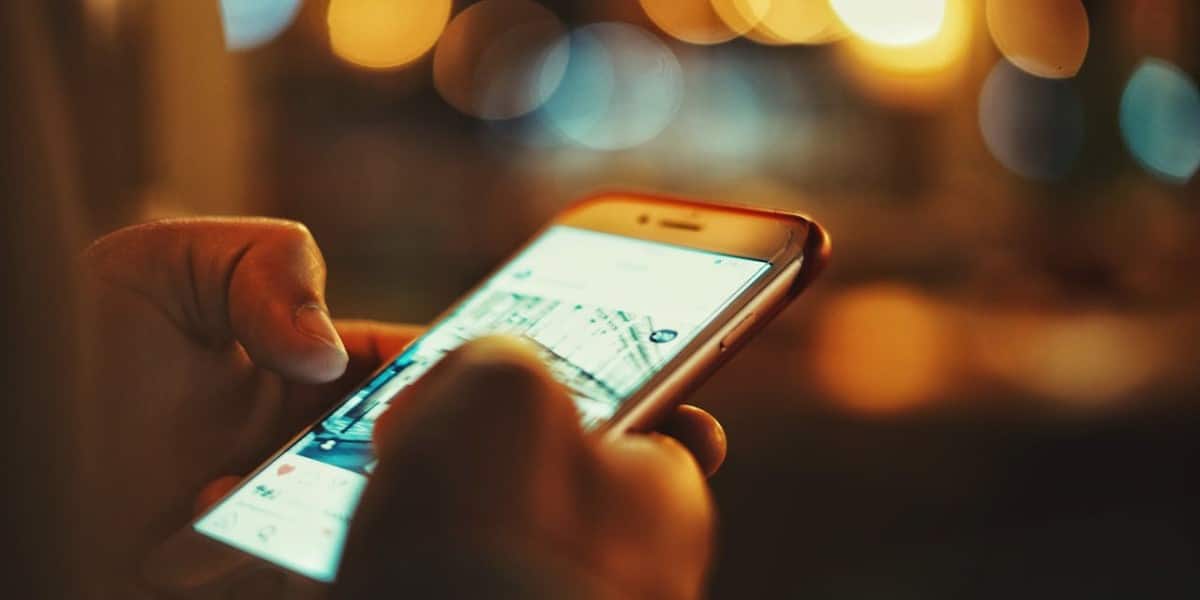 Detalhe mostrando celular nas mãos de uma pessoa, enquanto ela observa um post do Instagram. Qual tamanho post Instagram.
