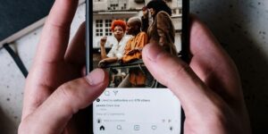 Detalhe mostrando celular nas mãos de uma pessoa, com tela ligada no feed do Instagram, enquanto o usuário procura onde fica os rascunhos do Instagram.