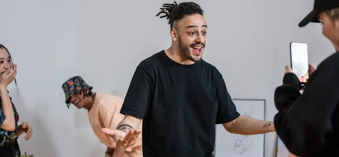 4 jovens gravando um vídeo para TikTok. Um rapaz filma com o celular, enquanto outro rapaz e duas jovens interagem, rindo, espontâneos. Comprar visualizações TikTok