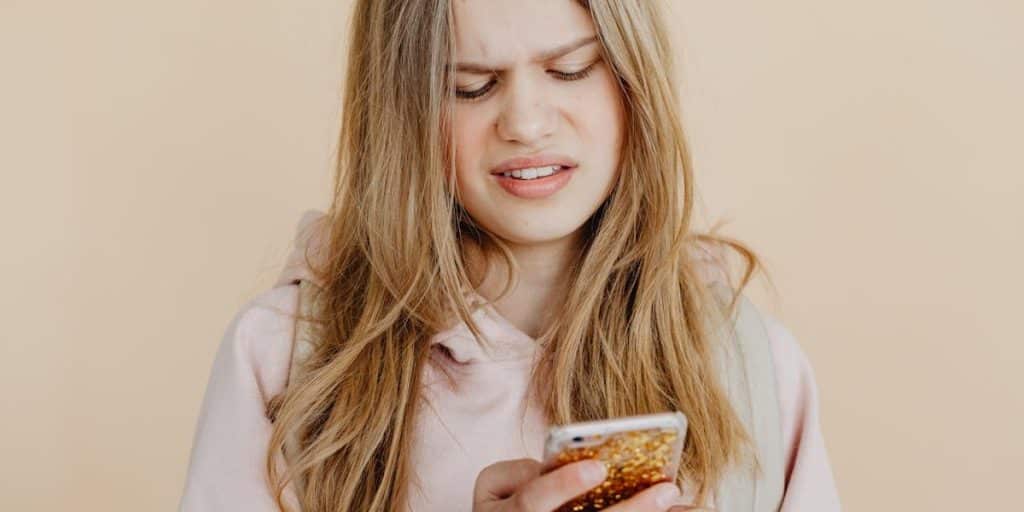 Jovem segura celular e faz cara de preocupação, pensando no engajamento do Instagram