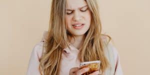 Jovem segura celular e faz cara de preocupação, pensando no engajamento do Instagram